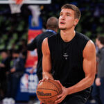 Serbian NBA basketball player Bogdan Bogdanović holding a basketball while practicing a shot on the court.