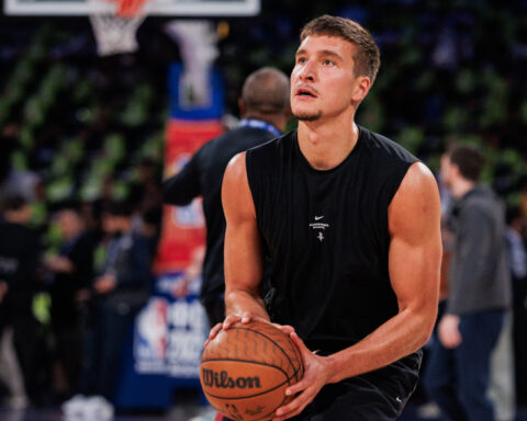 Serbian NBA basketball player Bogdan Bogdanović holding a basketball while practicing a shot on the court.