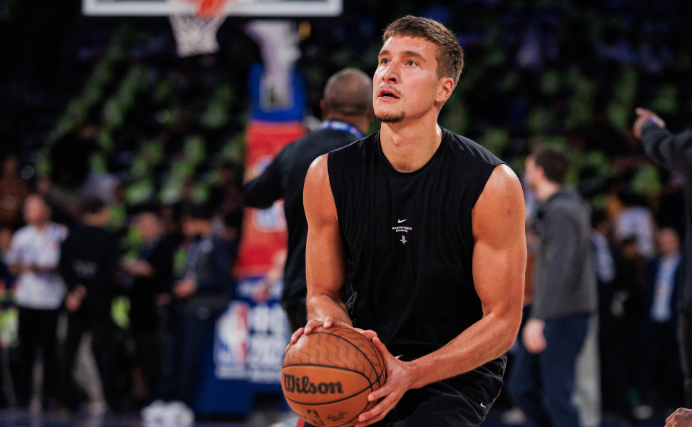 Serbian NBA basketball player Bogdan Bogdanović holding a basketball while practicing a shot on the court.