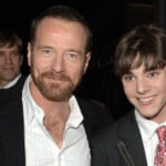 Bryan Cranston and RJ Mitte smiling together at an event, both wearing suits.
