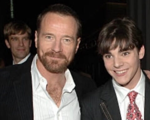 Bryan Cranston and RJ Mitte smiling together at an event, both wearing suits.