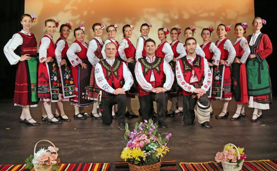 Gorana Dance ensemble members posing on stage in colorful traditional Bulgarian folk costumes.