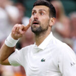 Serbian tennis star Novak Djokovic wearing a white tennis shirt during a match.