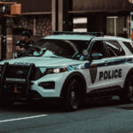 Police SUV parked on a city street with an officer standing nearby.