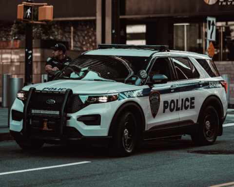 Police SUV parked on a city street with an officer standing nearby.