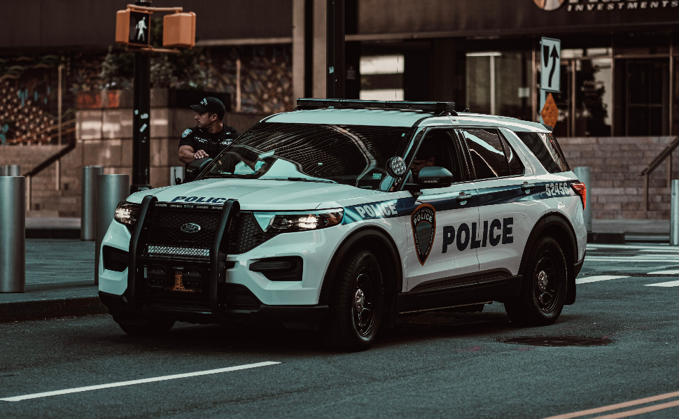 Police SUV parked on a city street with an officer standing nearby.