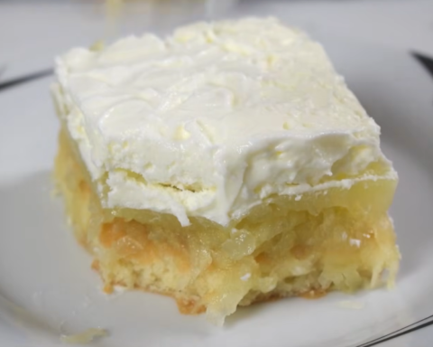 A slice of Yugoslavian apple cake with sponge cake, apple filling and whipped cream, served on a white plate.