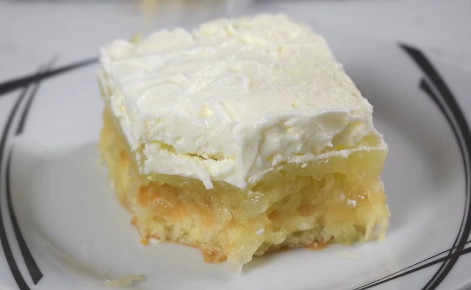 A slice of Yugoslavian apple cake with sponge cake, apple filling and whipped cream, served on a white plate.