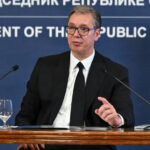 Aleksandar Vučić speaking at an official press conference in Serbia, seated behind microphones.
