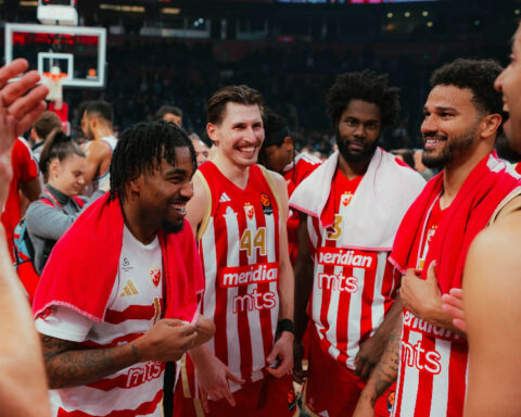 Crvena Zvezda basketball players celebrating together on the court after a EuroLeague game in Belgrade.