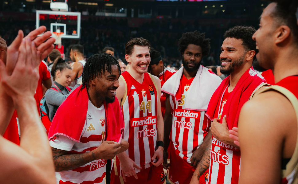 Crvena Zvezda basketball players celebrating together on the court after a EuroLeague game in Belgrade.