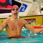 Croatian swimmer Jere Hribar celebrates in the swimming pool with his fists raised after a race.