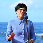 European Commissioner for Enlargement Marta Kos speaking at a podium with the European Union flag in the background.