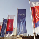 NIS and Gazprom Neft corporate flags flying outside a building in Serbia.