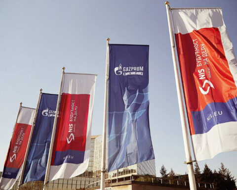 NIS and Gazprom Neft corporate flags flying outside a building in Serbia.