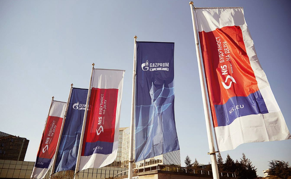 NIS and Gazprom Neft corporate flags flying outside a building in Serbia.