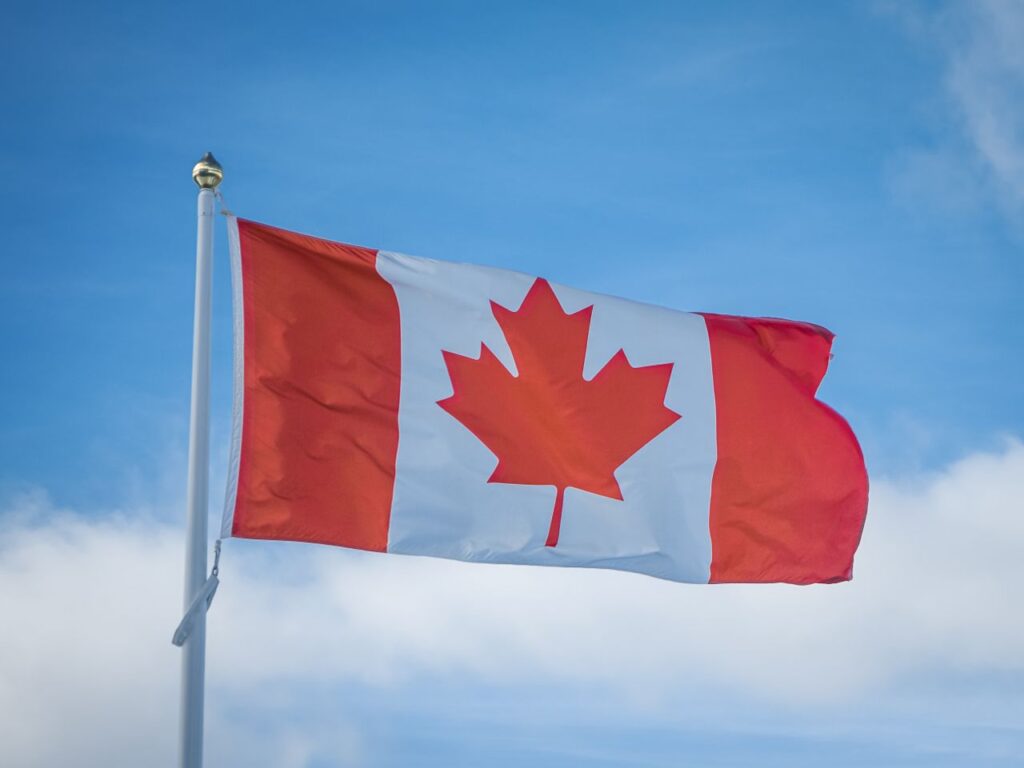 Canadian national flag waving against a blue sky, illustrating the Alberta separation referendum and Canada's national unity.