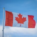 Canadian national flag waving against a blue sky, illustrating the Alberta separation referendum and Canada's national unity.