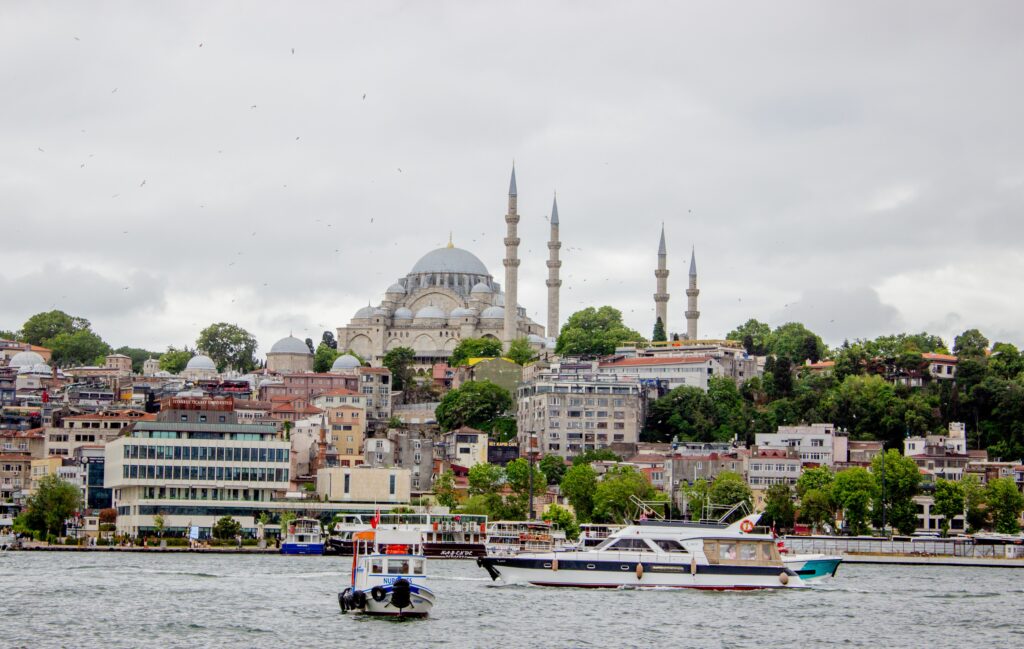 Istanbul skyline with a historic mosque and boats on the waterfront.