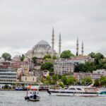 Istanbul skyline with a historic mosque and boats on the waterfront.