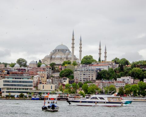 Istanbul skyline with a historic mosque and boats on the waterfront.