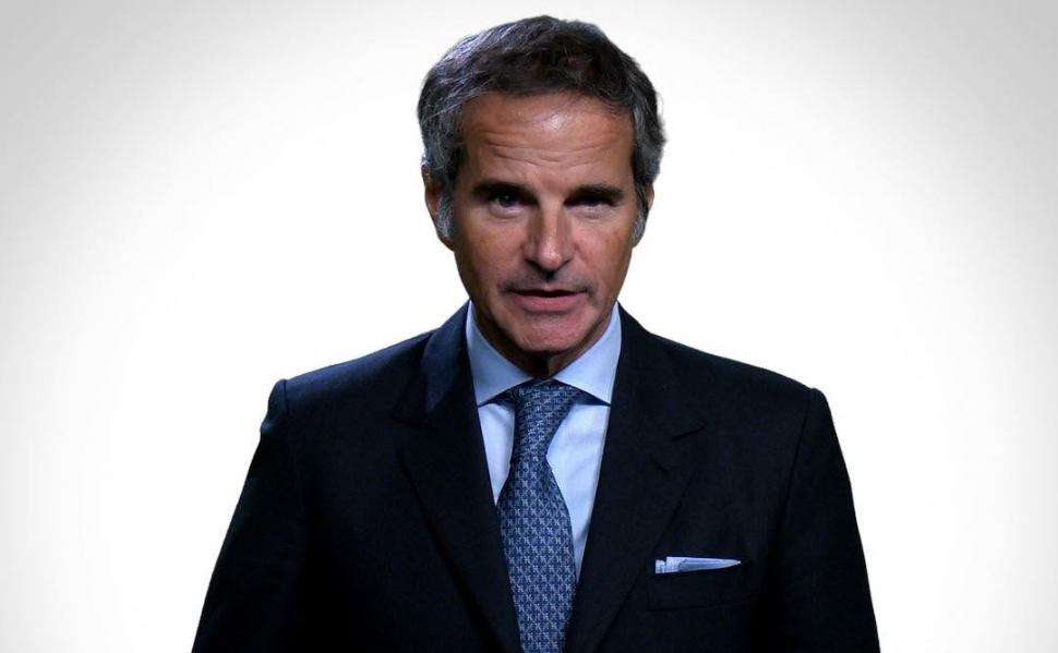 IAEA Director General Rafael Grossi wearing a dark suit and blue tie against a white background.