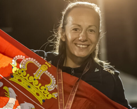 Serbian women's minifootball player smiling while holding the Serbian national flag and wearing a medal.