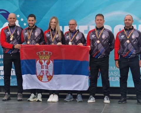 Serbian paragliders posing with the Serbian national flag and their medals at the 2026 European Paragliding Accuracy Championship in Romania.