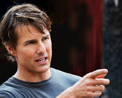 Hollywood actor Tom Cruise wearing a gray T-shirt and pointing during a conversation.