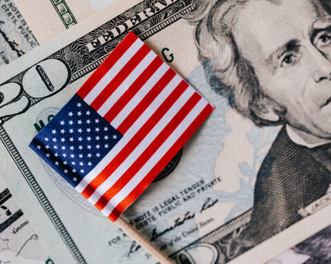 Small American flag resting on US dollar banknotes, including a twenty-dollar bill.