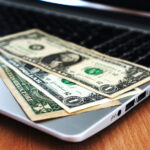 US dollar banknotes resting on a laptop computer keyboard