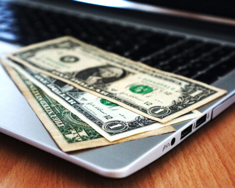 US dollar banknotes resting on a laptop computer keyboard