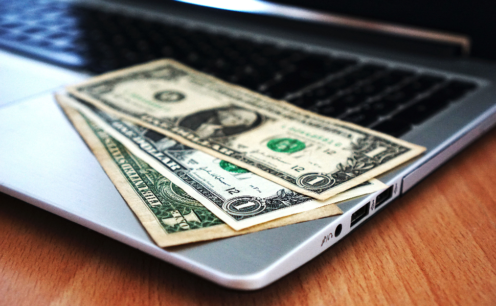 US dollar banknotes resting on a laptop computer keyboard