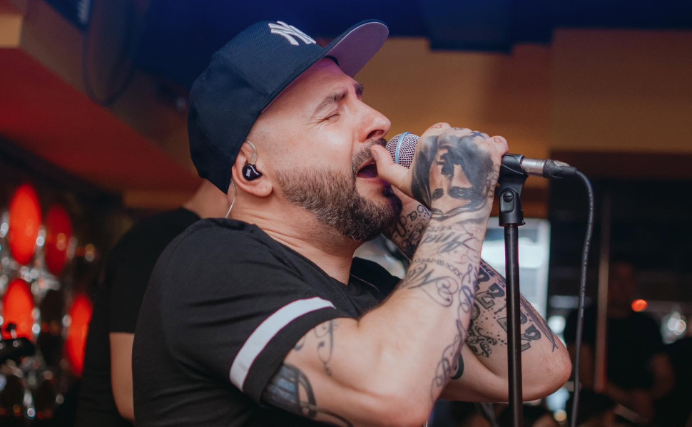 Vladimir Blažev Pancho, member of Macedonian music duo DNK, singing into a microphone during a live performance.